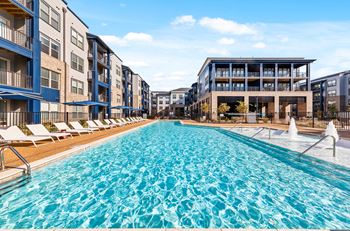 A large swimming pool in front of apartment buildings.